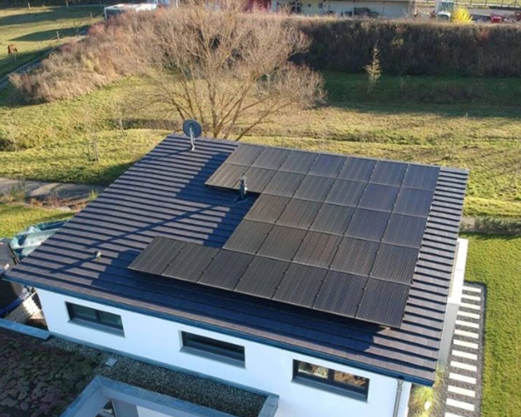 Draufsicht eines kleinen Hauses in einem grünen Garten mit Solarpanelen auf dem Dach