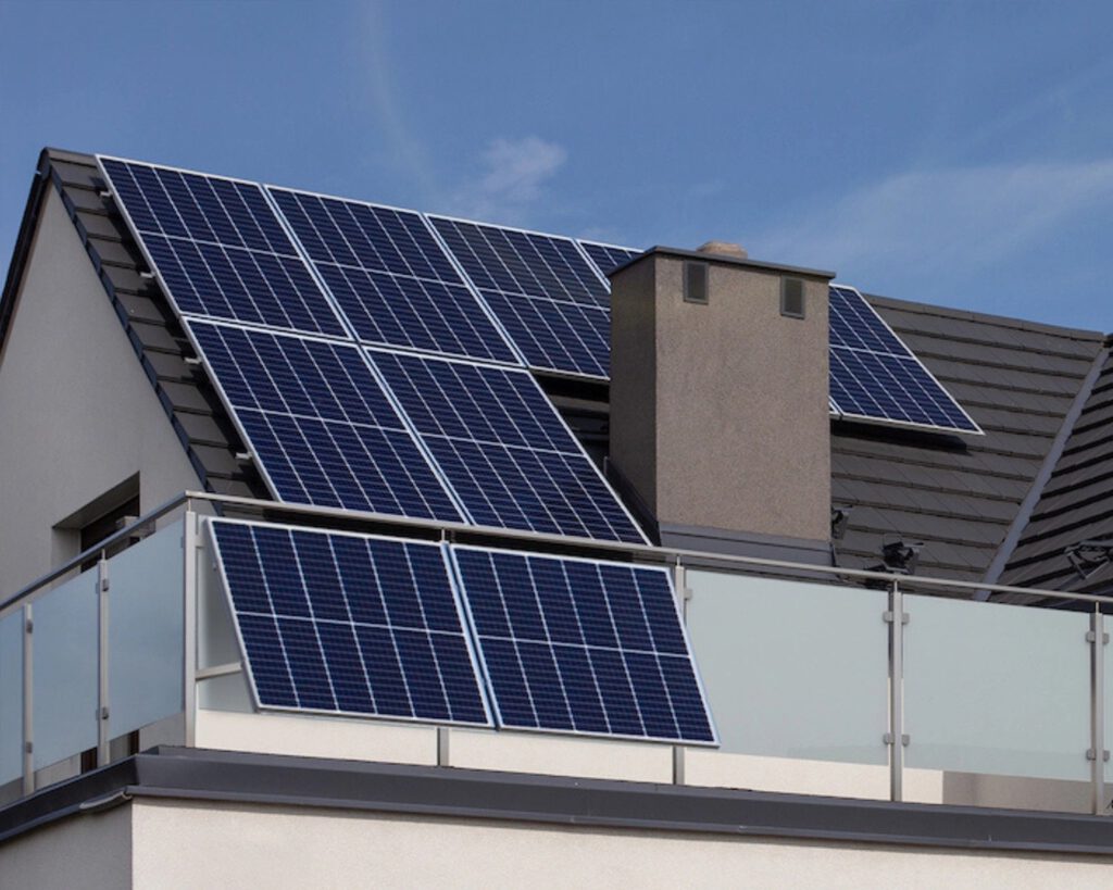 Grau gekacheltes Satteldach mit Schornstein und Solarpanelen darauf